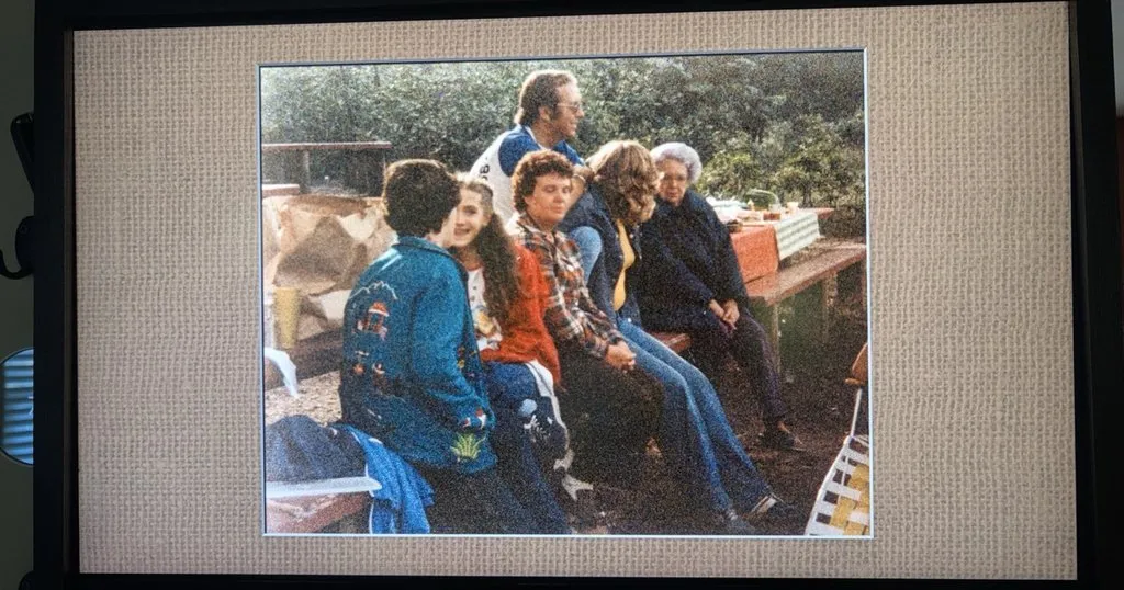 A digital picture frame built from an old TV, showing a matted vintage family photo on a wall