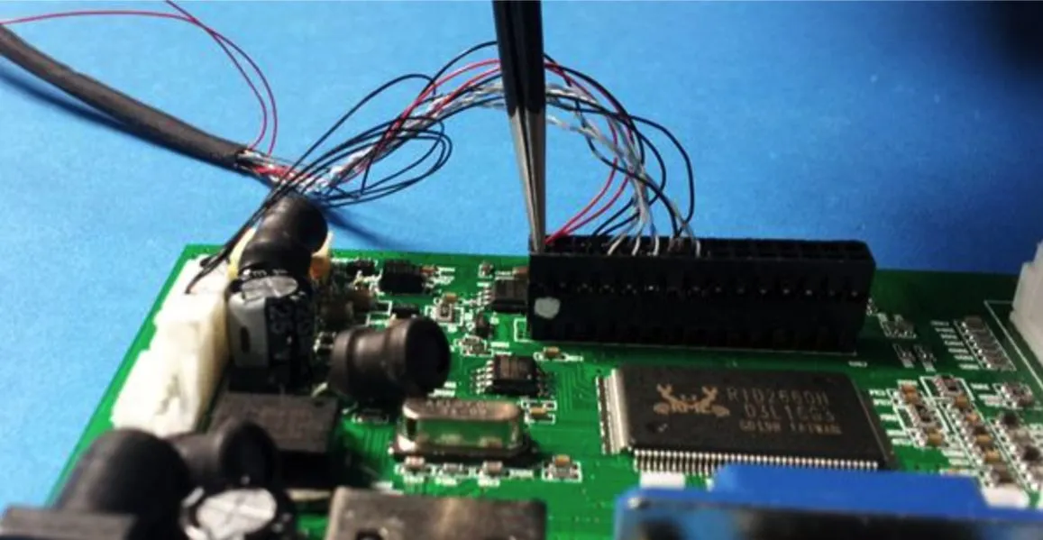 Tweezers seating fine wires from a display cable into the connector of a green LCD controller board