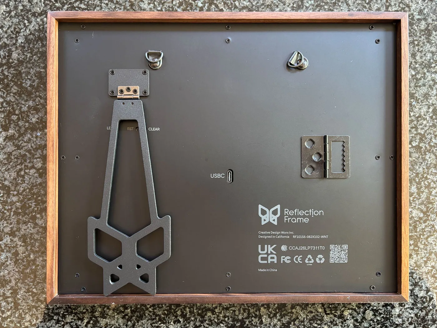 The back of the 10-inch Reflection Frame in walnut with its butterfly-shaped stand, wall hangers and USB-C port