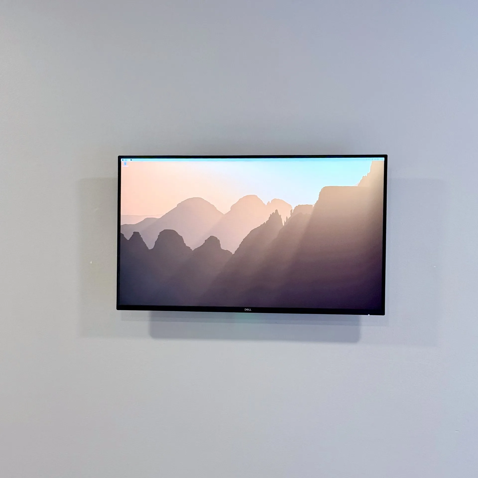 A bare Dell monitor on the wall showing a plain desktop