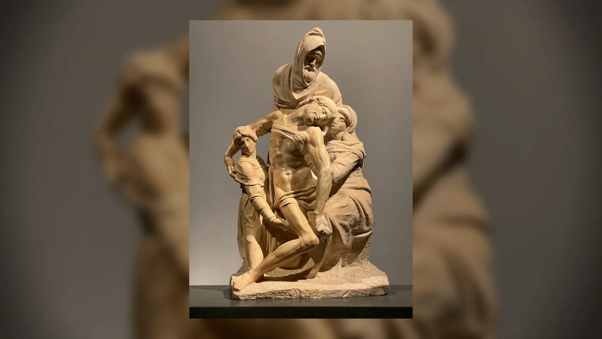A marble Pietà sculpture, sharp in the center, floating over a softly blurred and enlarged copy of itself